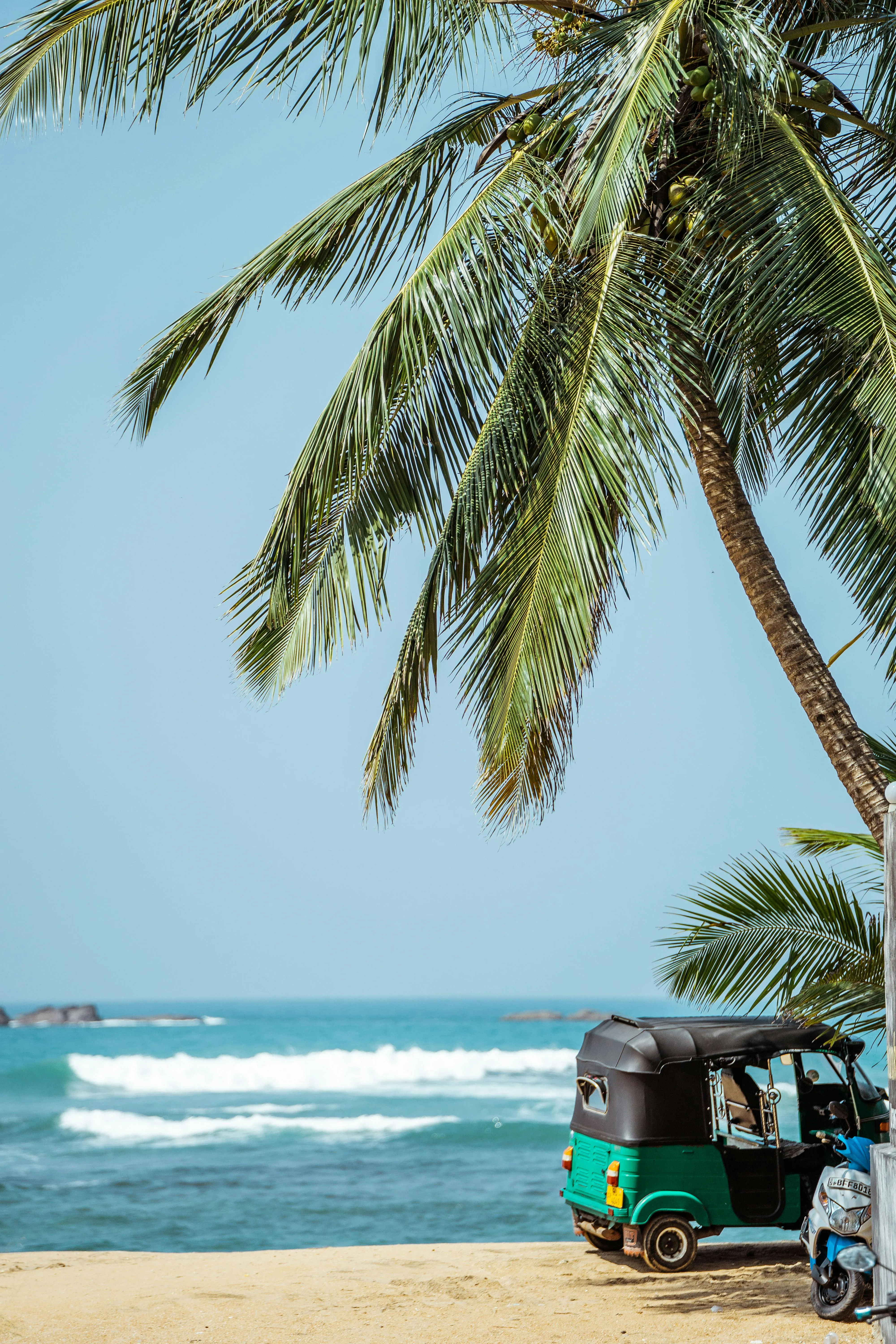 Sri Lankan beach with sand and ocean and green tuktuk 